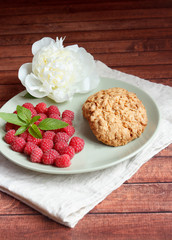 Delicious cookies with raspberries, mint and white peony flower on the plate.