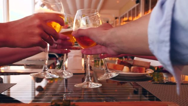 Friends clink glasses with alcohol in a restaurant by the sea. close-up. slow motion