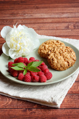 Delicious cookies with raspberries, mint and white peony flower on the plate.