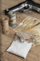 Money, drugsand a gun on a wooden table
