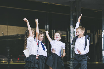 Beautiful school children active and happy on the background of school in uniform