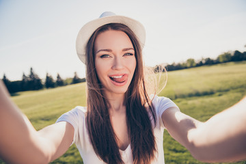 Playful funky selfie mood! Happy young girl on vacation in an open air spring park is making...