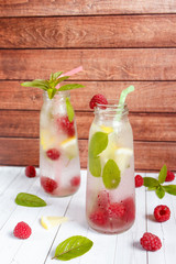 Cold cocktail with raspberries, lemon and mint. Wooden background