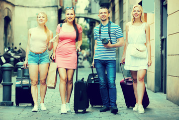 Four friendly traveling persons walking in city