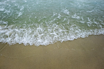 wave of green ocean on sandy beach