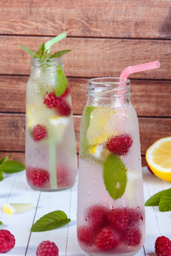 Cold cocktail with raspberries, lemon and mint. Wooden background