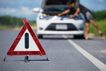 Red emergency stop sign and white car after accident on the road