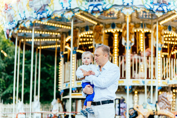 Father and son playing in amusement park at the evening time. Concept of friendly family