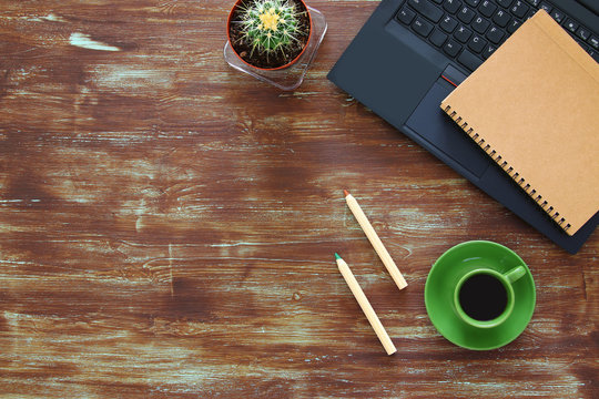 Top view of office work table with leptop, notebbok and cup of coffee