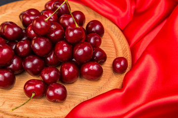 Large red dark cherries on a wooden stand with red cloth