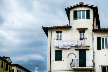Fototapeta na wymiar Clothes hanged to dry on the facade of a house in Lucca, Italy.