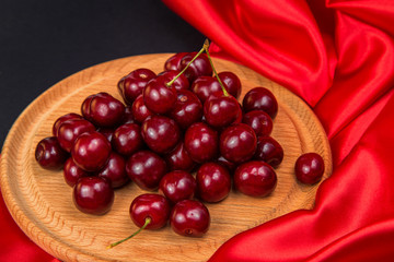 Large red dark cherries on a wooden stand with red cloth