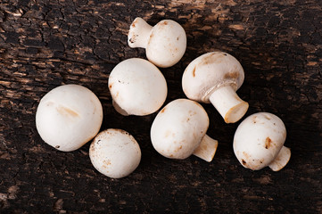 Mushrooms champignons on an old wooden background.