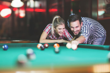 Young couple playing together pool in bar