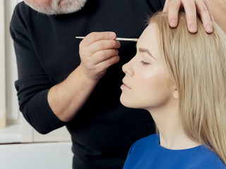 Woman getting makeup on face with brush in male hand