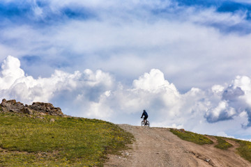 Cyclist on the horizon on a background of clouds.