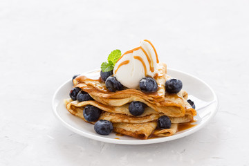 Crepes served with fresh blueberries, ice cream and caramel sauce