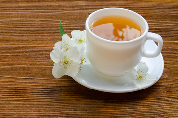 Obraz na płótnie Canvas White mug of tea with jasmine on a wooden table. Close up, top view
