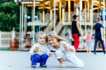 Smiling two kids eat ice cream and looking at each other