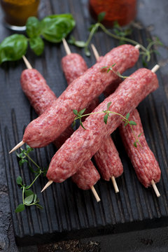 Close-up of raw fresh cevapcici or skinless beef sausages on skewers, selective focus, studio shot