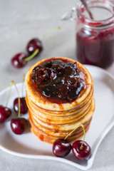 Homemade American pancakes served with cherry jam and fresh cherry on a wooden background