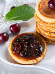 Homemade American pancakes served with cherry jam and fresh cherry on a wooden background