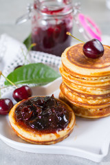 Homemade American pancakes served with cherry jam and fresh cherry on a wooden background