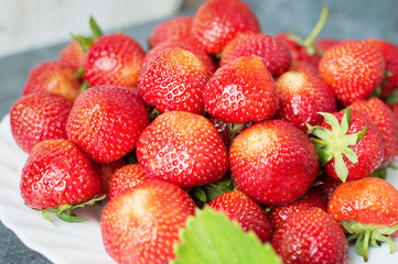 Red strawberries and green leaves on a black background