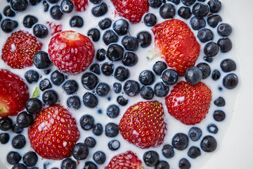 Strawberries, blueberries and milk in a white bowl
