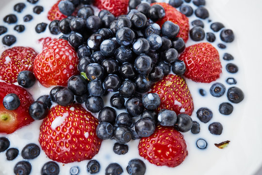 Strawberries, blueberries and milk in a white bowl