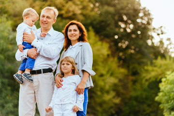 Fototapeta premium Happy family of father, mother and two children, baby son and daughter in the summer park.