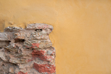 Classic facade. Old stone wall and yellow plaster. Brick in the wall