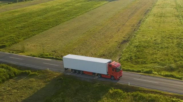 Aerial shot of a truck on the road in beautiful countryside in the summer.

