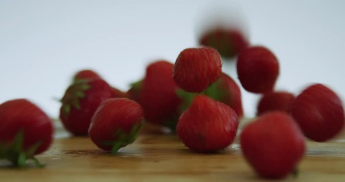 Erdbeeren fallen auf ein Holzbrett - Brettchen - Holz - Close
