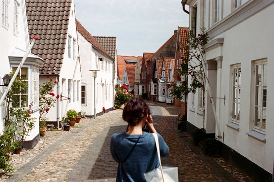 Rear View of Woman Photographing on Street Amidst Houses