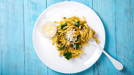 Fetuchini Pasta with sauce. Hot dish with Parmesan cheese, decorated with green parsley on a blue background.Copy space for Text.selective focus.