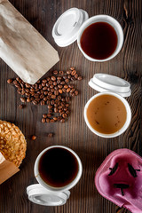 Coffee take out. Coffee cups with covers, coffee beans and cookies on wooden table backound top view