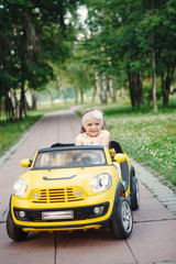 Little girl rides on toy electric cars yellow in the Park