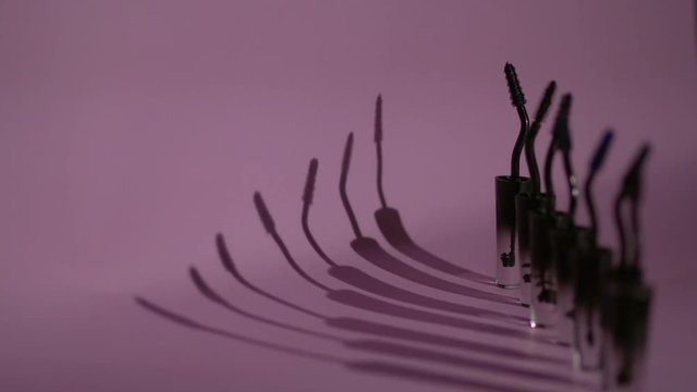 Brushes for mascara stand in a row on a purple background.