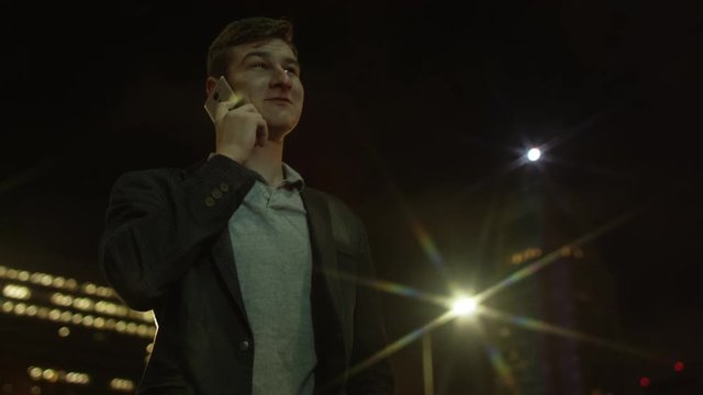 Joyful young tourist is calling someone over his smartphone on a street