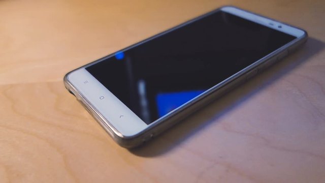 Smart phone with blank screen lying on wooden table