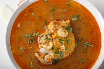 Chicken soup with noodles and vegetables in white bowl