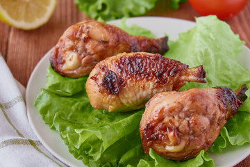 Grilled chicken legs with vegetables and lemon on a wooden background