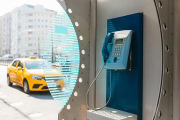 Street payphone with yellow taxi in the background. Travel concept, passenger transportation,...