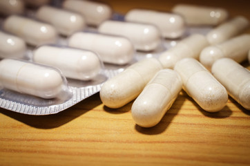Herb capsule medicine on the wooden surface. Closeup