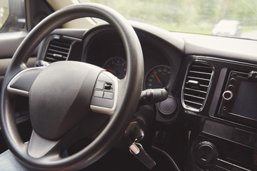 The wheel of the moving car with no hands on it. There is other car on the counter side of the road. Inside view.