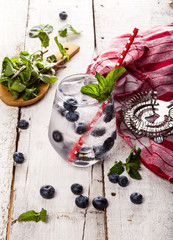 Summer cold drink with blueberry, mint and ice on white wooden background