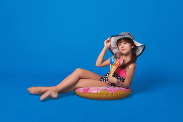 Fototapeta na wymiar Beautiful girl in swimsuit and beach hat resting with ice cream. Space for text