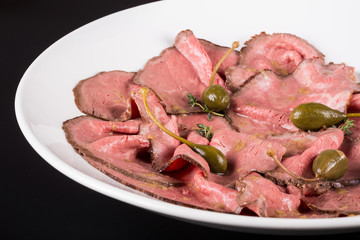 Plate of cold cuts with capers.Cutting meat on a plate with capers. Close up