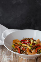 Noodles with vegetables and seafood on a wooden table Chinese-style noodles with vegetables and seafood. copy space.